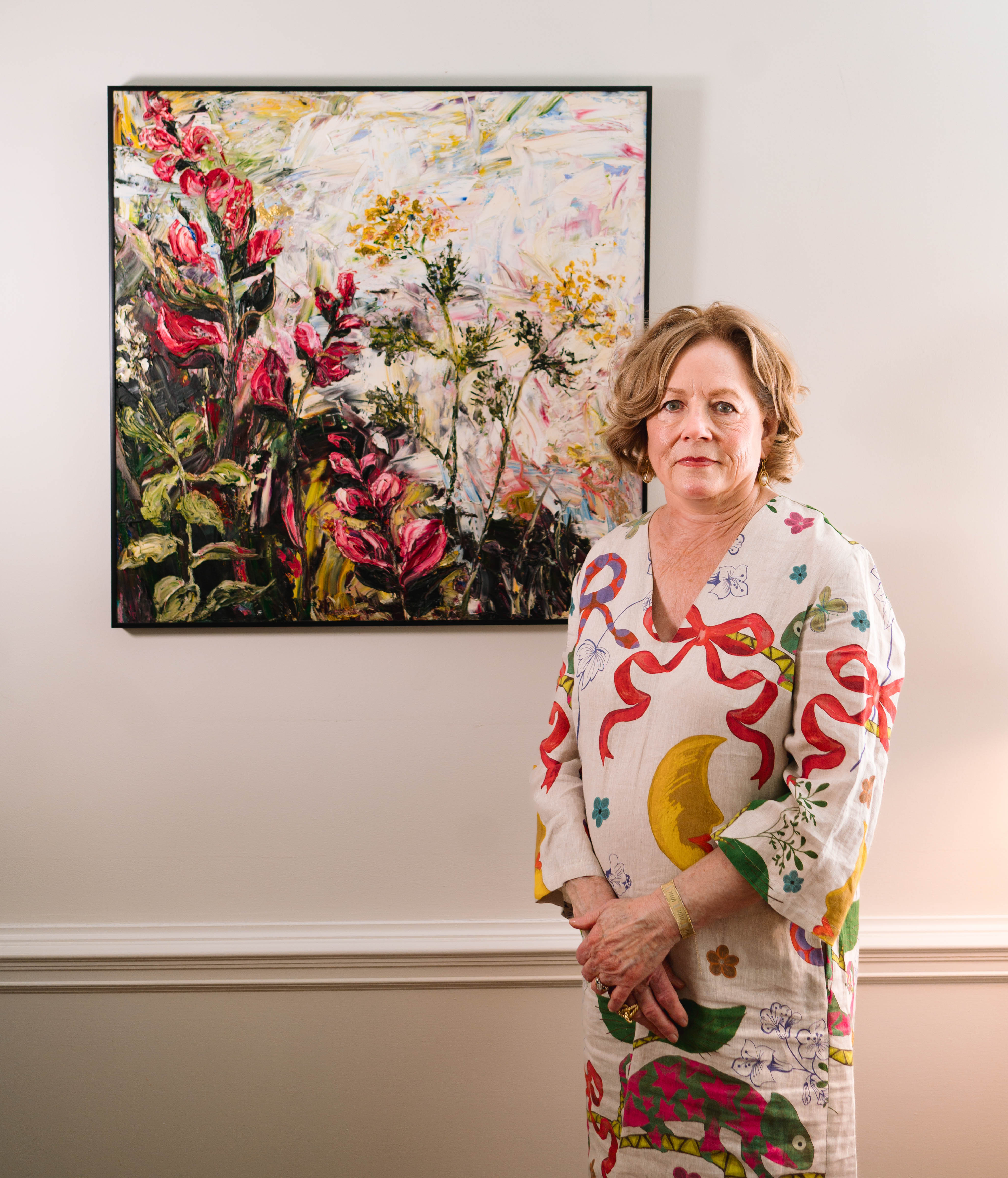 Beverly Walker standing in front of one of her large floral paintings